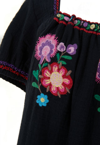 close-up-of-a-black-embroidered-blouse-featuring-vibrant-floral-patterns-in-pink-purple-blue-and-green-with-red-and-purple-trim-along-the-neckline